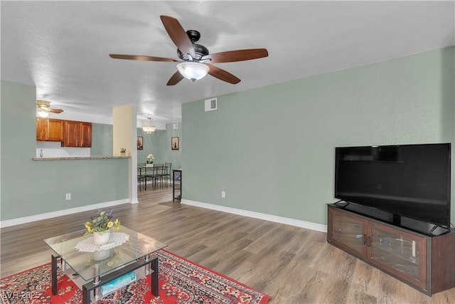 living room with ceiling fan, wood finished floors, and baseboards
