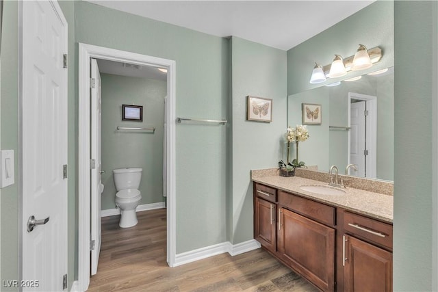 bathroom with wood finished floors, vanity, toilet, and baseboards