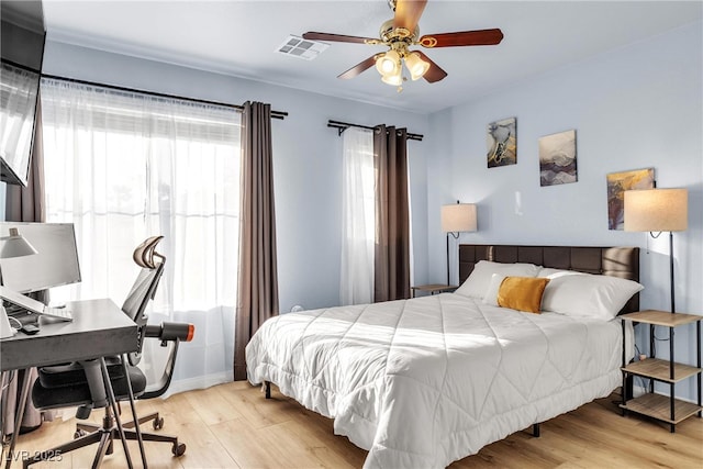 bedroom with wood finished floors, an office area, and ceiling fan