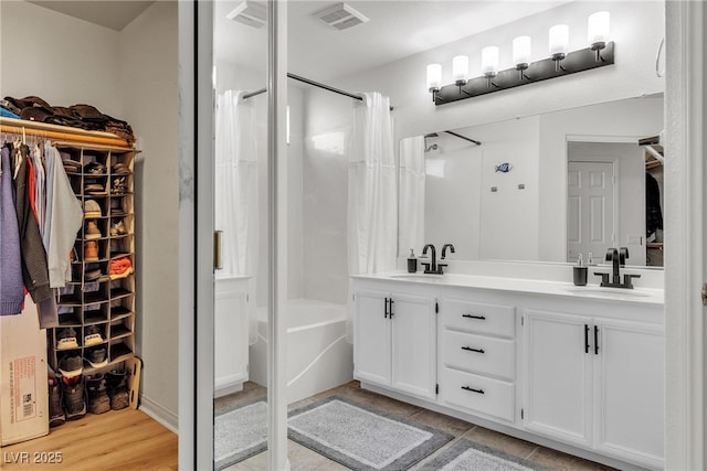 bathroom with double vanity, a walk in closet, and shower / bath combination with curtain
