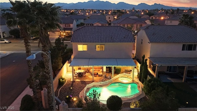 back of property at dusk with stucco siding, a residential view, a patio area, and a fenced backyard