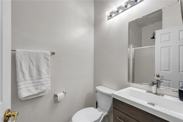 bathroom with toilet, a shower with door, and vanity