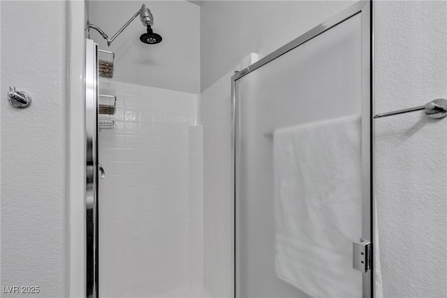 full bathroom with a shower stall and a textured wall