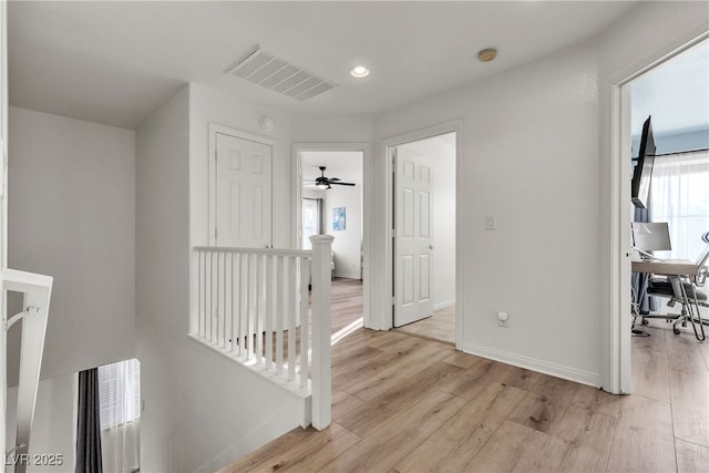 hallway featuring an upstairs landing, light wood finished floors, baseboards, a desk, and recessed lighting