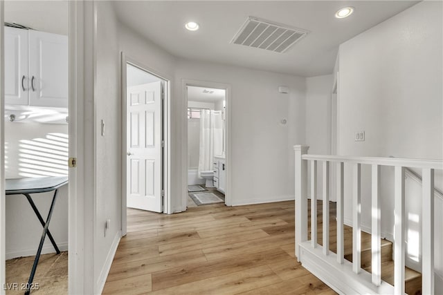 corridor featuring light wood-style flooring, recessed lighting, baseboards, and an upstairs landing