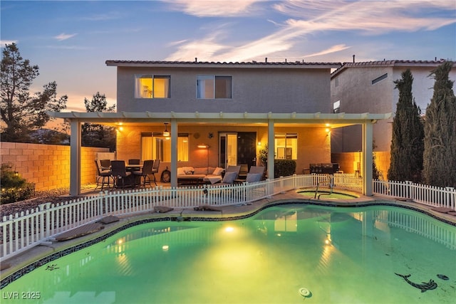 pool at dusk with an outdoor living space, a fenced backyard, and a patio