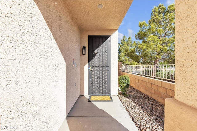 entrance to property with stucco siding and fence