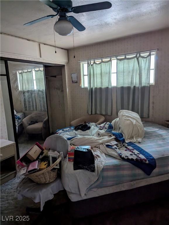 bedroom featuring a ceiling fan, a textured ceiling, and a closet