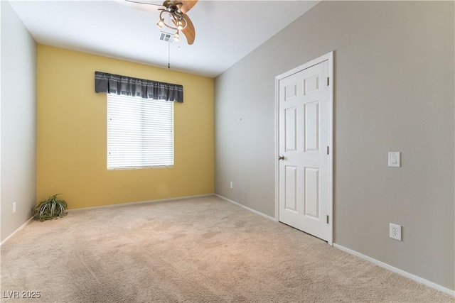 carpeted spare room with a ceiling fan and baseboards