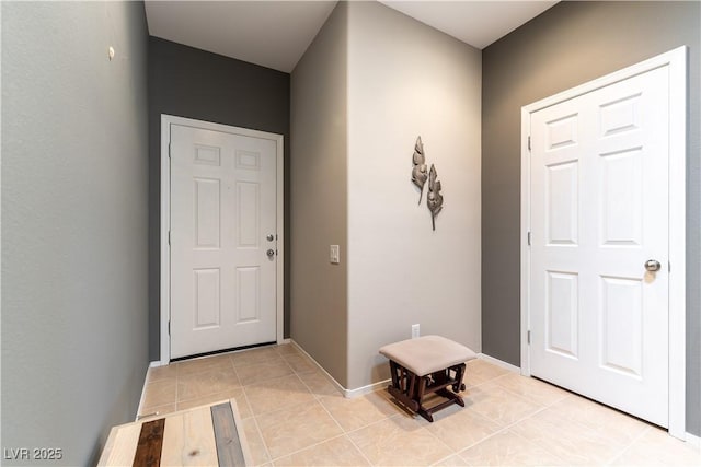 foyer featuring light tile patterned floors and baseboards