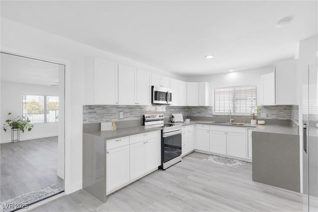 kitchen featuring appliances with stainless steel finishes, a sink, healthy amount of natural light, backsplash, and recessed lighting