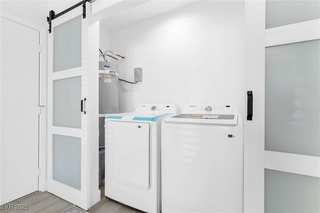 laundry area featuring washing machine and dryer, light wood-style flooring, and a barn door