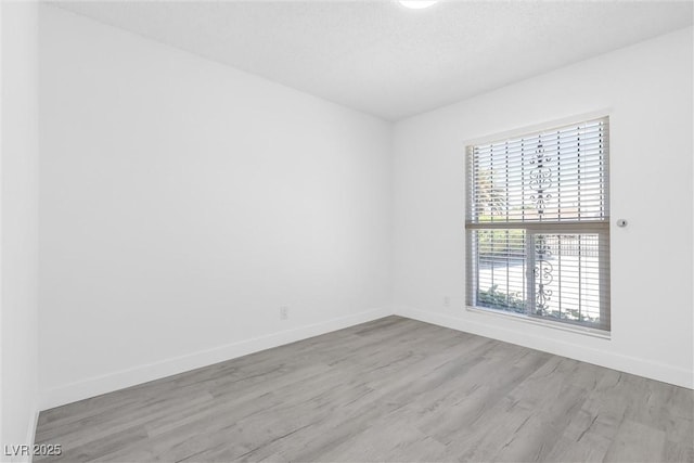 spare room featuring wood finished floors and baseboards