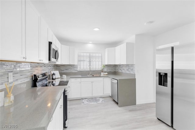kitchen with appliances with stainless steel finishes, a sink, light stone counters, white cabinetry, and recessed lighting