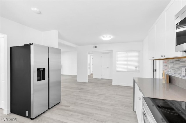 kitchen with stainless steel appliances, white cabinetry, baseboards, light wood-style floors, and a fireplace