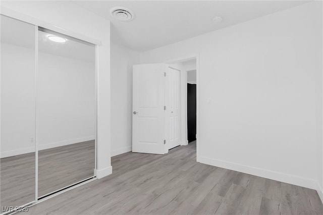 unfurnished bedroom with baseboards, wood finished floors, and a closet