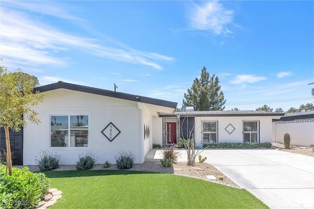 ranch-style house with a front lawn, stucco siding, and concrete driveway