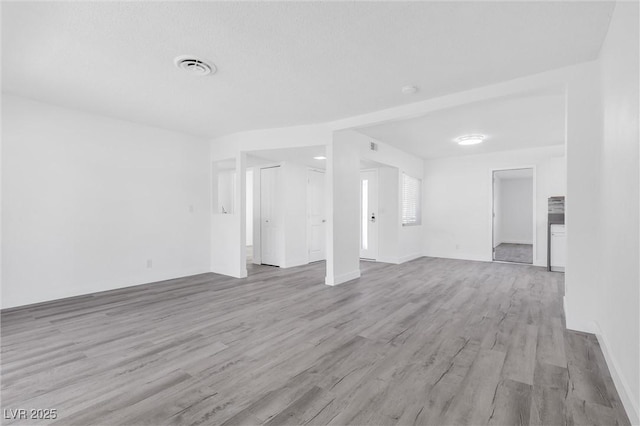 unfurnished living room with light wood-type flooring and baseboards