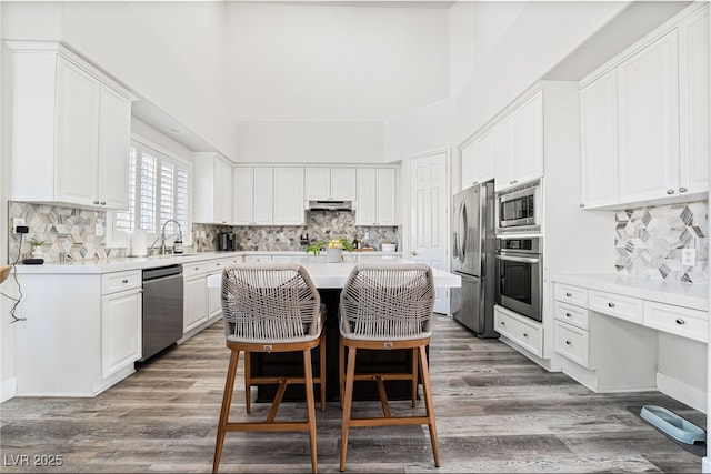5684 Benevento Ct, Las Vegas, NV 89141 - kitchen with stainless steel appliances, under cabinet range hood, a kitchen island, light countertops, and decorative backsplash