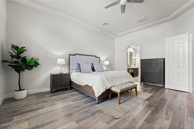 5684 Benevento Ct, Las Vegas, NV 89141 - bedroom with wood finished floors, arched walkways, ceiling fan, baseboards, and ensuite bath