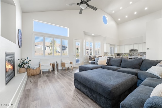 5684 Benevento Ct, Las Vegas, NV 89141 - living room featuring light wood-style flooring, recessed lighting, high vaulted ceiling, a glass covered fireplace, and a ceiling fan