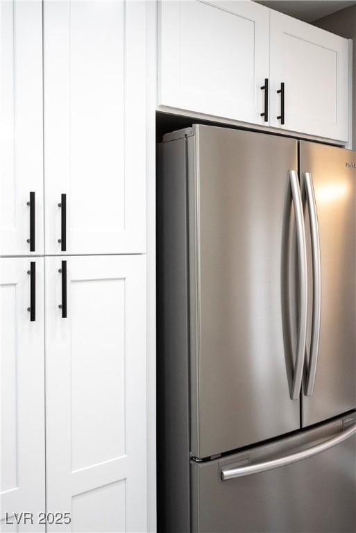 detailed view of freestanding refrigerator and white cabinetry