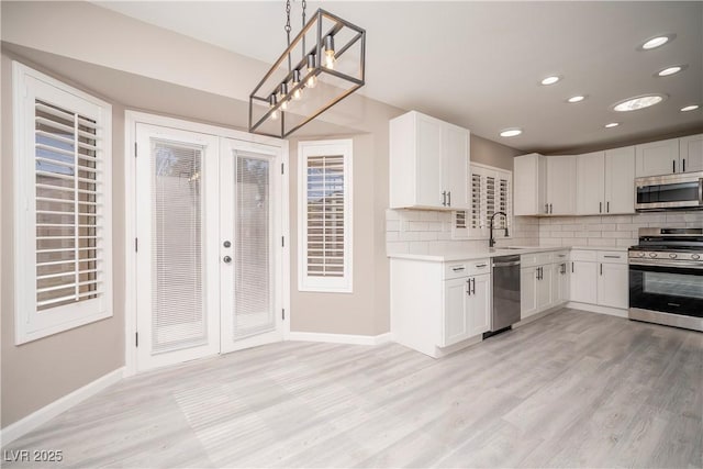 kitchen featuring appliances with stainless steel finishes, a sink, french doors, light countertops, and baseboards