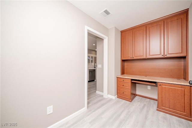 unfurnished office with light wood finished floors, baseboards, and built in desk