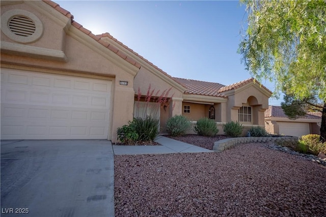 view of front of house featuring a tile roof, driveway, stucco siding, and a garage