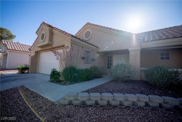 view of front of home featuring a tiled roof, an attached garage, stucco siding, and driveway