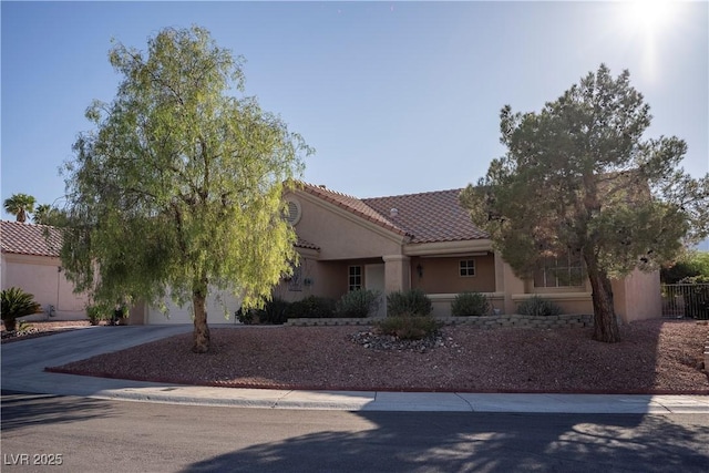 view of front of property with stucco siding, concrete driveway, a tile roof, a garage, and fence