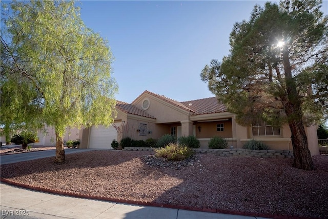 view of front of property featuring stucco siding, driveway, a tile roof, and an attached garage
