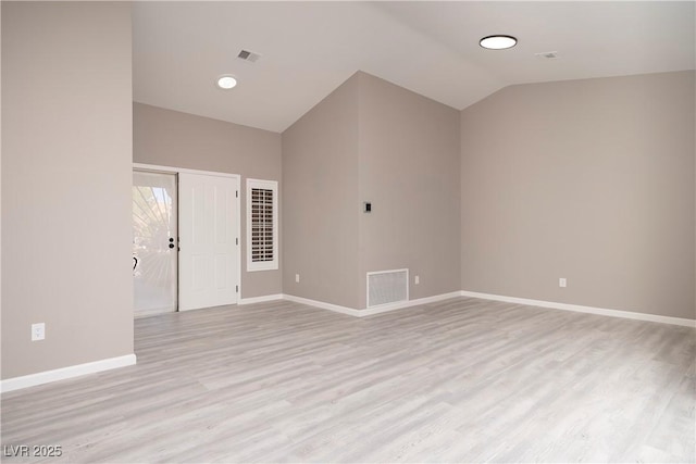 spare room featuring light wood-type flooring, baseboards, and lofted ceiling