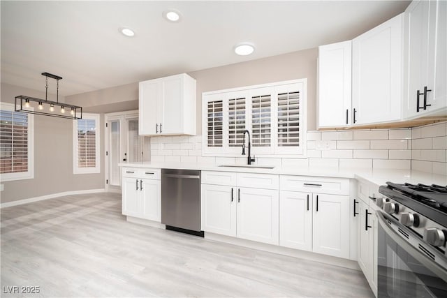 kitchen with stainless steel dishwasher, a sink, light countertops, decorative backsplash, and light wood-style floors