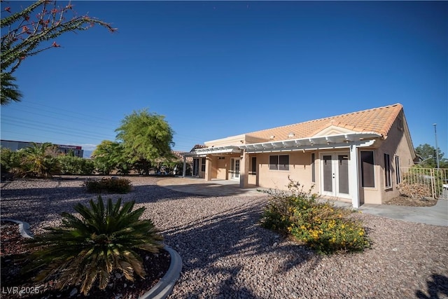 back of house featuring stucco siding, a patio area, french doors, a pergola, and a tiled roof