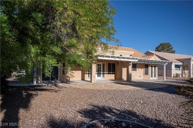 back of property with stucco siding, a patio, a tiled roof, fence, and french doors