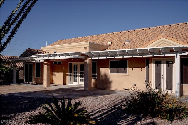 back of property with french doors, a pergola, a tile roof, and stucco siding