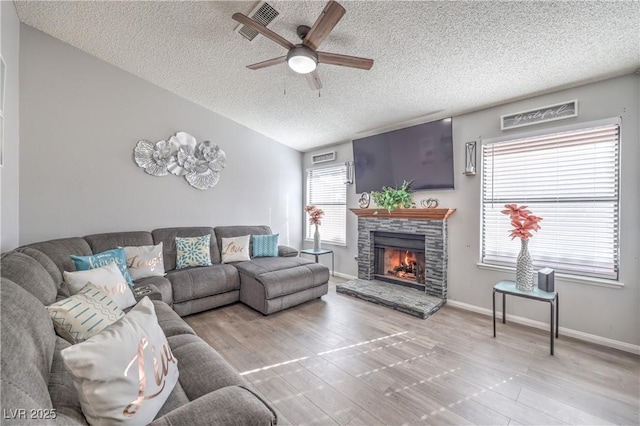 6408 Deadwood Rd, Las Vegas, NV 89108 - living area featuring a ceiling fan, a textured ceiling, a stone fireplace, wood finished floors, and baseboards