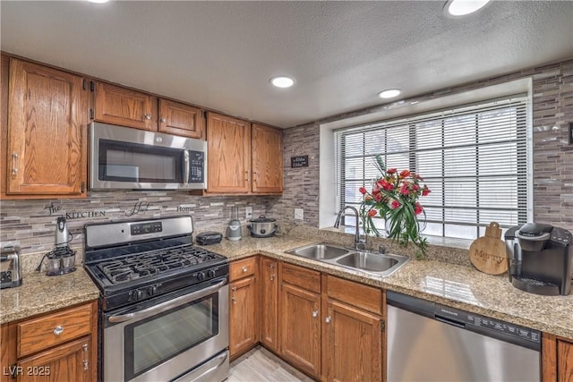 6408 Deadwood Rd, Las Vegas, NV 89108 - kitchen featuring appliances with stainless steel finishes, a sink, brown cabinets, decorative backsplash, and a textured ceiling
