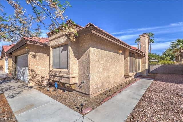 6408 Deadwood Rd, Las Vegas, NV 89108 - view of side of property with stucco siding, fence, a garage, and a tiled roof