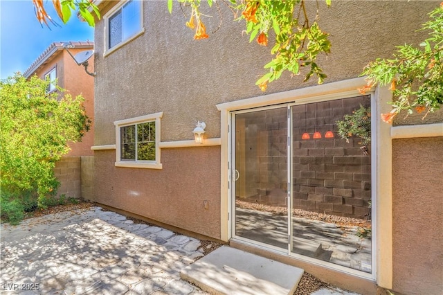 property entrance featuring stucco siding and a patio area