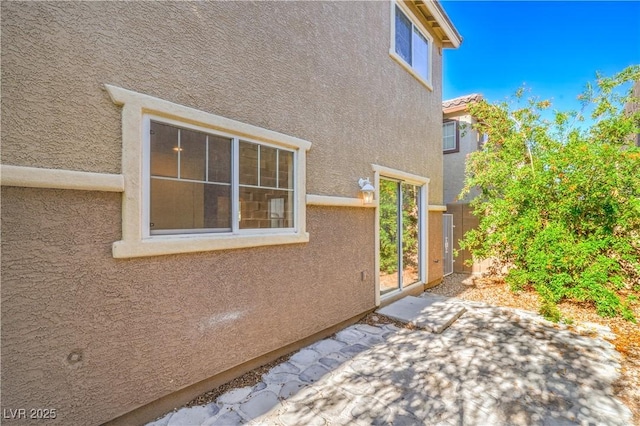 view of side of property with stucco siding and a patio