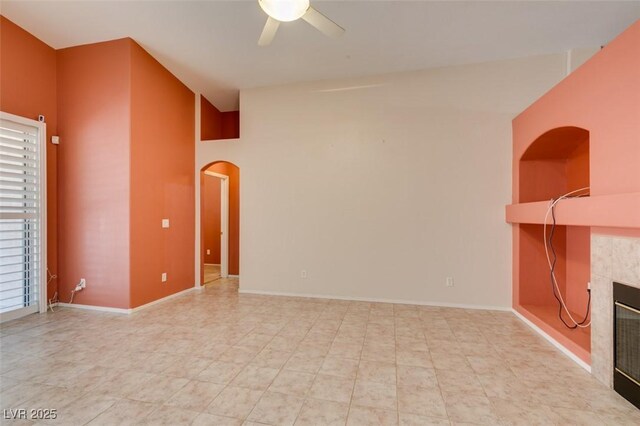 2587 Grizzly Park Ct, Henderson, NV 89052 - unfurnished room with arched walkways, ceiling fan, a fireplace, and baseboards