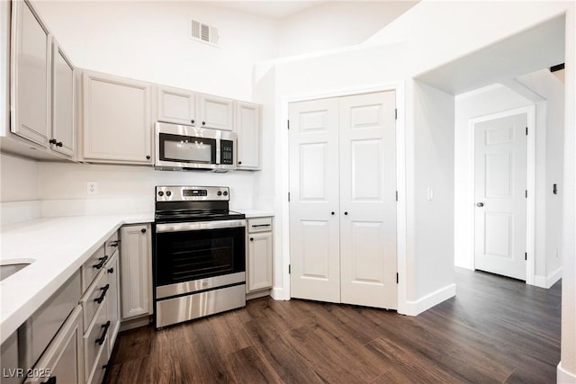kitchen featuring stainless steel appliances, dark wood-style flooring, and light countertops