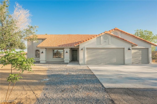 mediterranean / spanish-style house featuring a garage, concrete driveway, stucco siding, and a tile roof