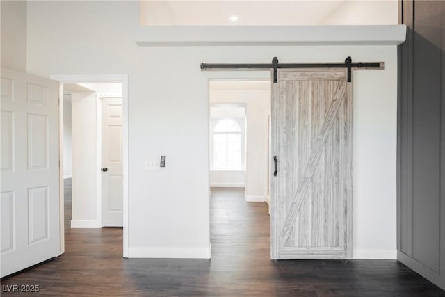 spare room with a barn door, baseboards, and dark wood finished floors