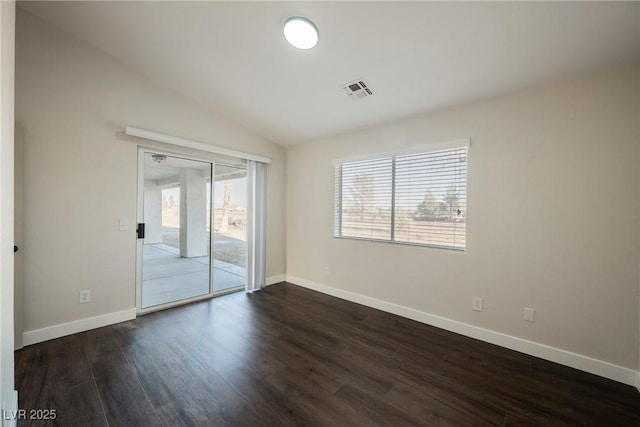 empty room featuring dark wood-style flooring, vaulted ceiling, and baseboards