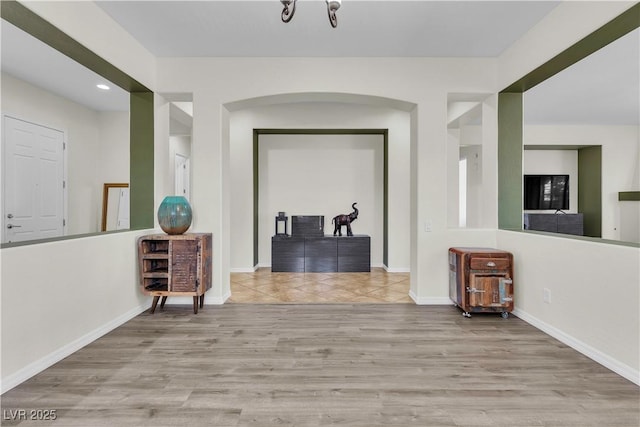 hall with wood finished floors, baseboards, arched walkways, and recessed lighting