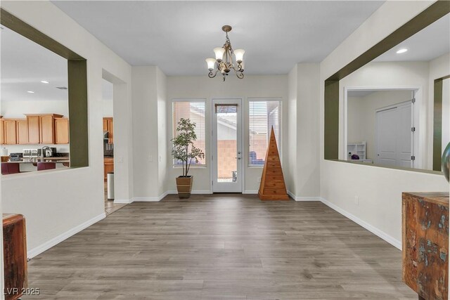 unfurnished dining area with a chandelier, wood finished floors, recessed lighting, and baseboards