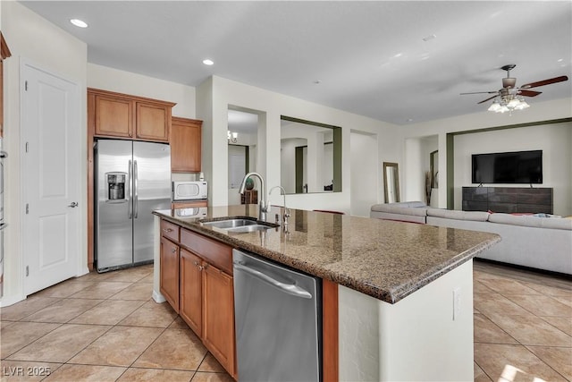 kitchen with stainless steel appliances, a sink, light tile patterned floors, ceiling fan, and dark stone counters